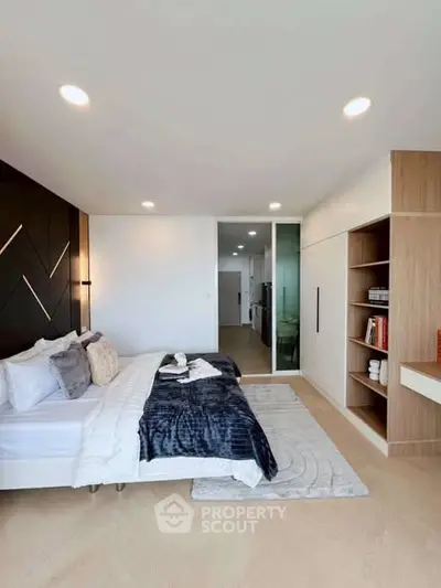 Modern bedroom with stylish decor and built-in shelving, featuring a cozy bed and elegant lighting.