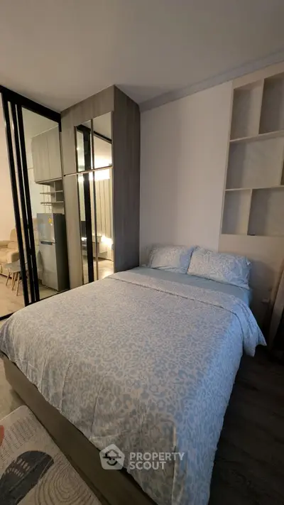 Cozy bedroom with modern decor and mirrored wardrobe in stylish apartment.