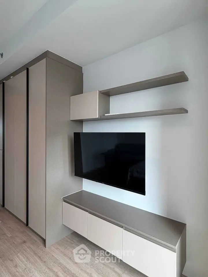 Modern living room with sleek TV unit and storage shelves in a stylish apartment.
