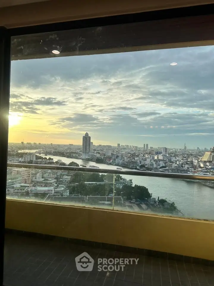 Stunning high-rise view of city skyline and river at sunset from a modern balcony.
