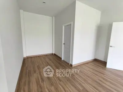 Spacious empty room with wooden flooring and white walls, ideal for customization.