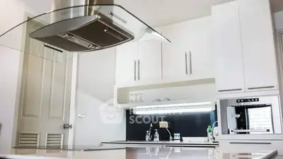 Modern kitchen with sleek cabinetry and built-in appliances, featuring a stylish range hood.