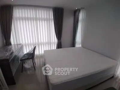 Spacious bedroom with large windows and modern furnishings in a bright apartment.
