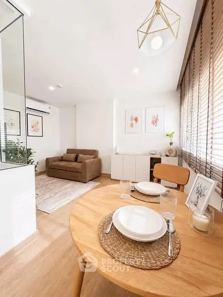 Bright and modern living room with dining area, featuring stylish decor and natural light.