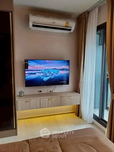 Modern living room with wall-mounted TV and air conditioning, featuring elegant decor and natural light.