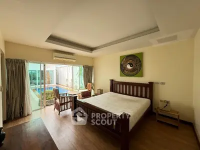 Spacious bedroom with pool view and elegant wooden furniture in a modern home.