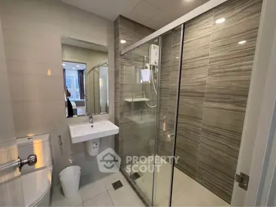 Modern bathroom with glass shower and sleek fixtures in contemporary apartment.