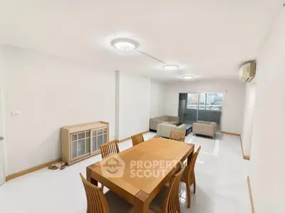 Spacious modern living room with dining area and city view balcony.