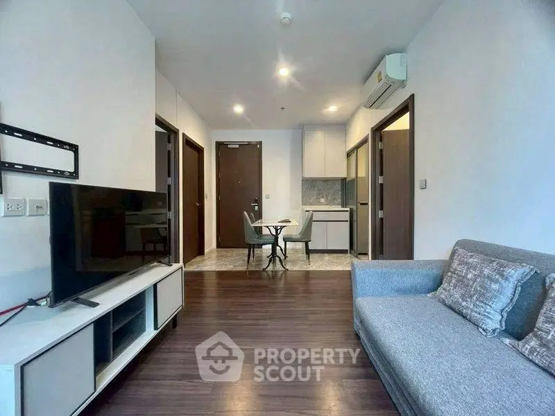 Modern living room with sleek furniture and open kitchen layout in a stylish apartment.