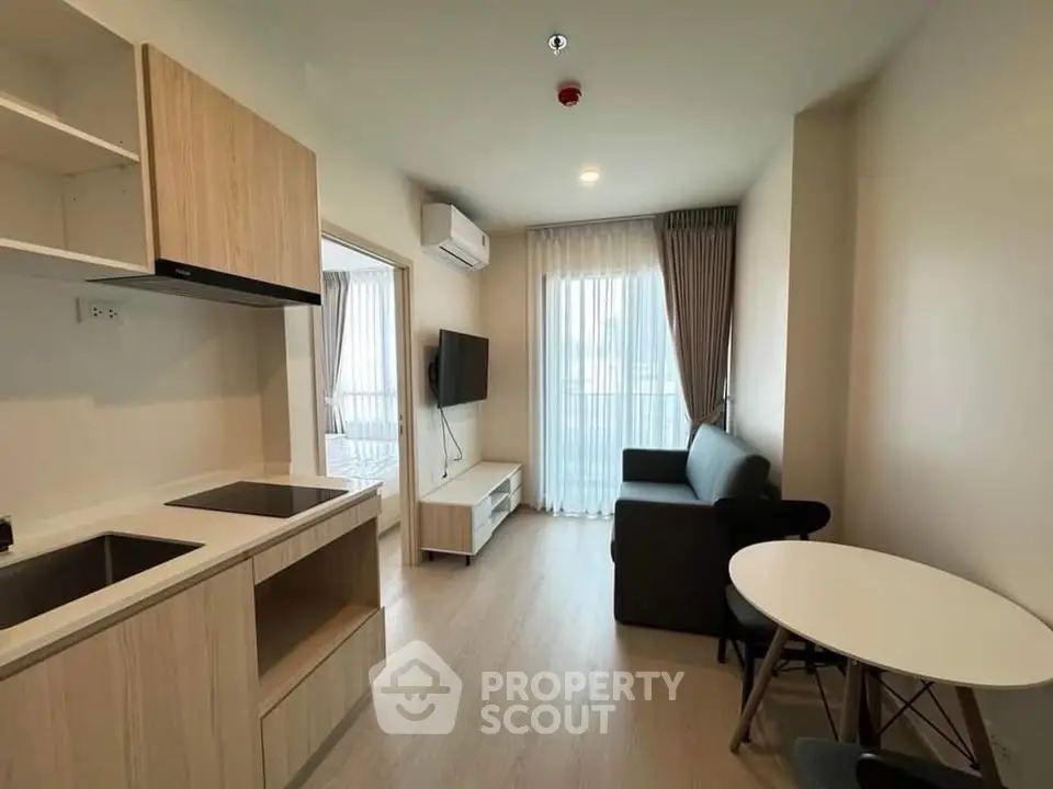 Modern living room with open kitchen, featuring sleek furniture and natural light.