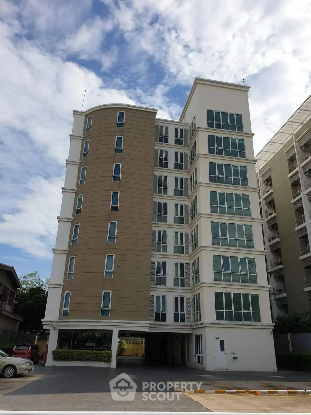 Modern multi-story apartment building with large windows and clear blue sky.