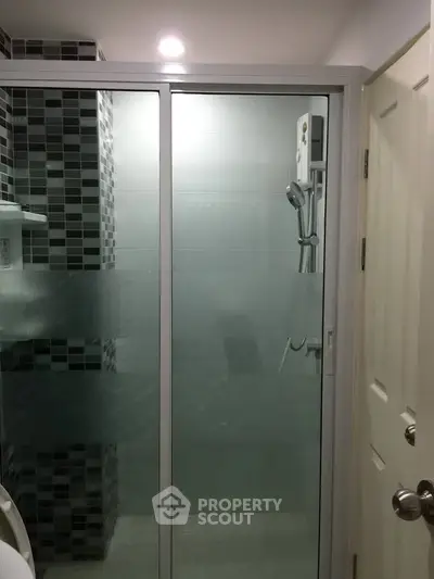 Modern bathroom with glass shower enclosure and sleek tile design.