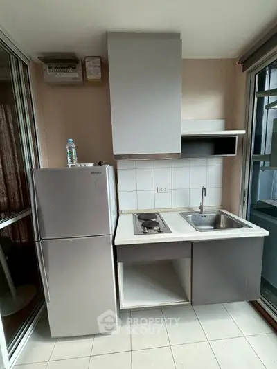 Compact kitchen with stainless steel fridge and electric stove in modern apartment