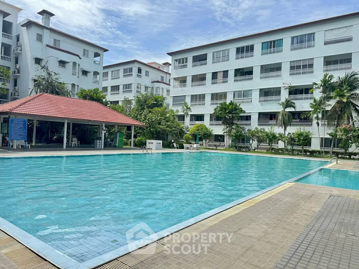 Spacious residential complex with a large swimming pool and lush greenery.