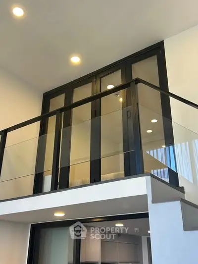 Modern duplex interior with sleek glass railing and high ceilings, showcasing contemporary design and spaciousness.