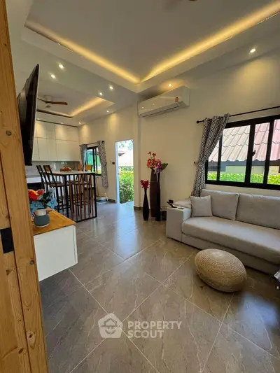 Modern living room with open kitchen, stylish decor, and natural light