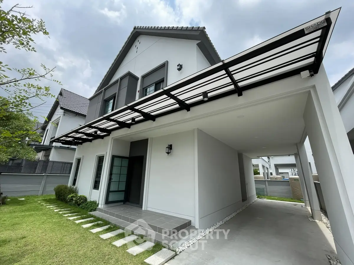 Modern two-story house with sleek design and spacious carport, surrounded by lush green lawn.