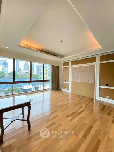 Spacious living room with wooden flooring and city view, perfect for modern living.