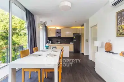 Modern open-layout kitchen and dining area with natural light and balcony view.