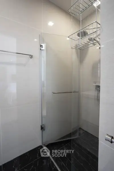 Modern bathroom with sleek glass shower and elegant black tile flooring.