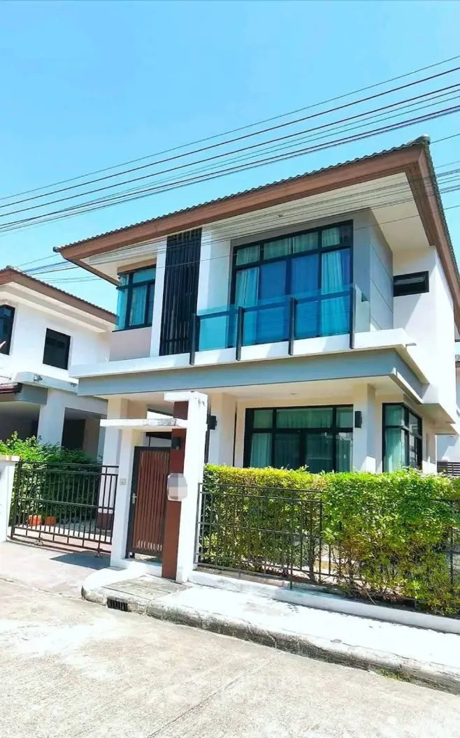 Modern two-story house with large windows and a well-maintained garden in a suburban neighborhood.