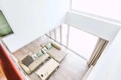 Spacious modern living room with large windows and stylish beige sectional sofa.