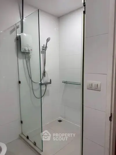 Modern bathroom with glass shower enclosure and sleek white tiles.