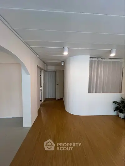 Spacious modern interior with wooden flooring and elegant archway, perfect for stylish living.