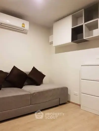 Modern living room with sleek sofa and wall-mounted storage in a cozy apartment.