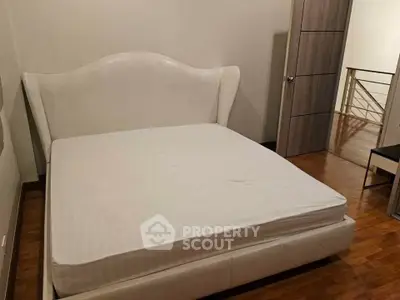 Spacious bedroom with elegant white bed and wooden flooring, perfect for a cozy retreat.