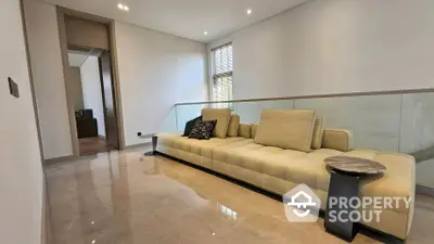 Spacious living room with polished tile flooring, modern beige sofa, and glass balustrade, offering a sleek and contemporary living space.