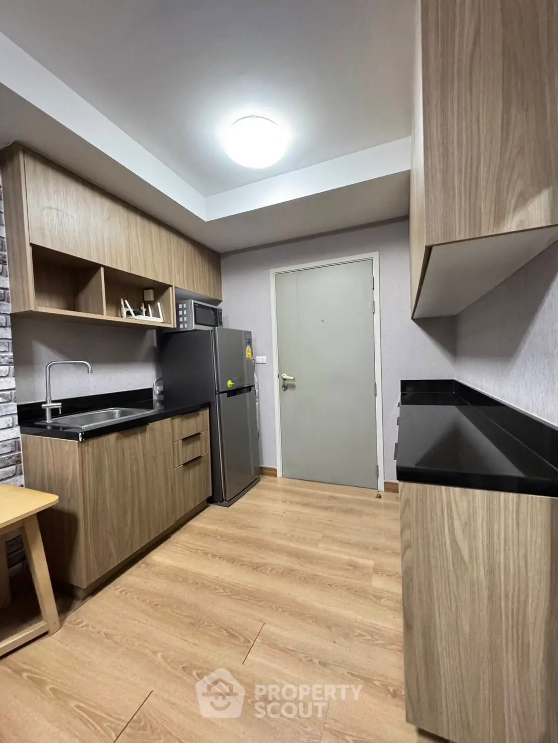 Modern kitchen with wooden cabinets and sleek black countertops in a cozy apartment.