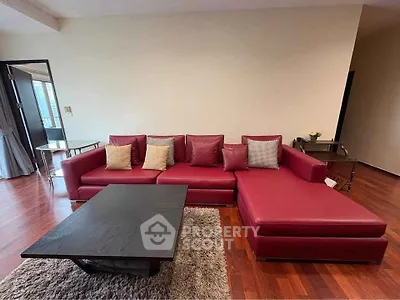 Spacious living room with elegant red sectional sofa and modern coffee table on hardwood floor.