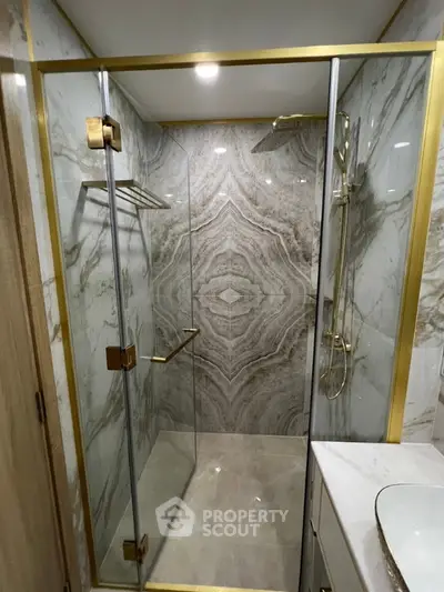 Luxurious marble bathroom with elegant glass shower enclosure and gold accents