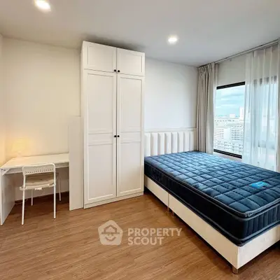 Modern bedroom with large window and study area, featuring a comfortable bed and sleek wooden flooring.