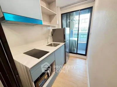 Modern compact kitchen with sleek appliances and balcony view
