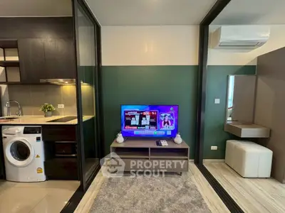 Modern living room with sleek kitchen and washing machine, featuring a stylish TV setup and air conditioning.
