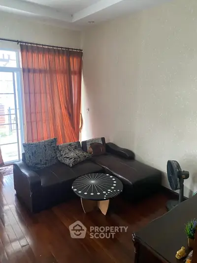Cozy living room with stylish sofa and modern decor, featuring wooden flooring and natural light.