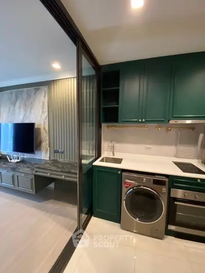 Modern kitchen with green cabinets, built-in appliances, and adjacent living area with TV.