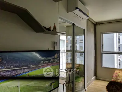 Modern living room with balcony access and air conditioning, featuring a large TV and stylish shelving.