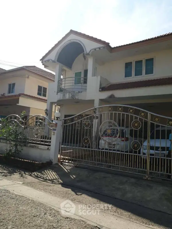 Charming two-story house with gated entrance and balcony in a sunny neighborhood.