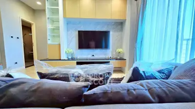 Modern living room with stylish decor and large TV, featuring elegant curtains and cozy seating area.