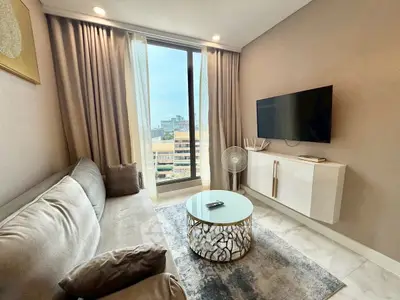 Modern living room with city view, sleek furniture, and wall-mounted TV.