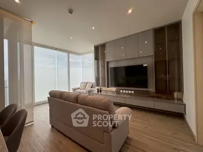Luxurious modern living room with sleek furniture and large TV, featuring floor-to-ceiling windows with stunning views.