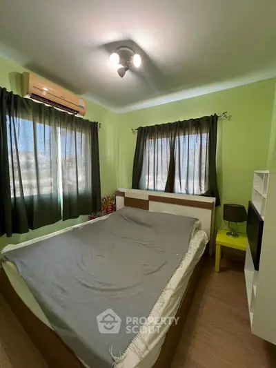Cozy bedroom with green walls, double bed, and air conditioning unit.