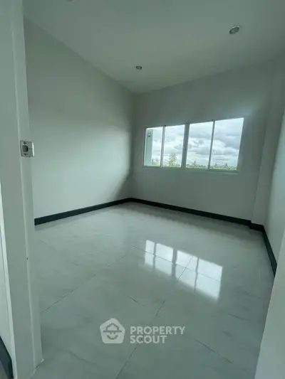 Spacious empty room with large window and tiled floor, perfect for customization.