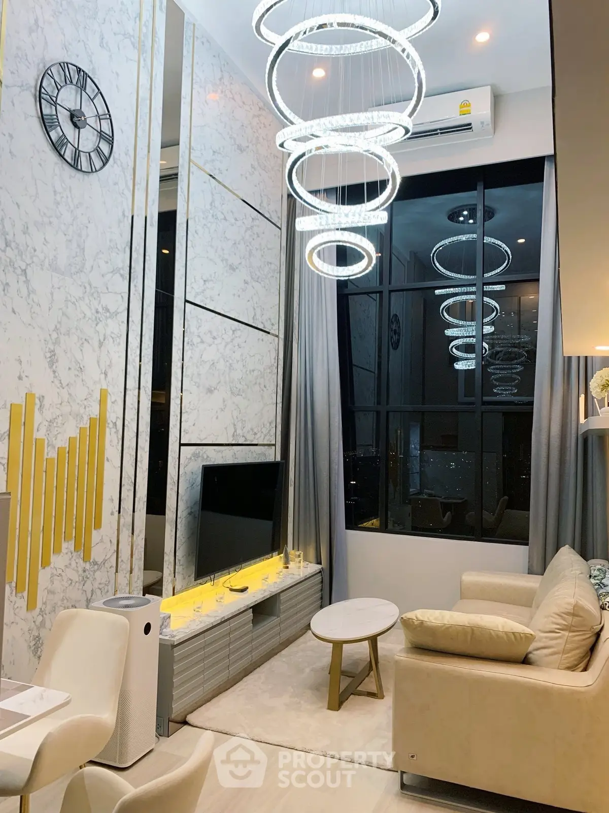 Luxurious modern living room with high ceiling, elegant chandelier, and stylish decor.