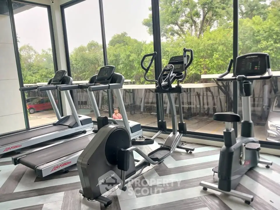 Modern gym with state-of-the-art fitness equipment and large windows offering a scenic view.