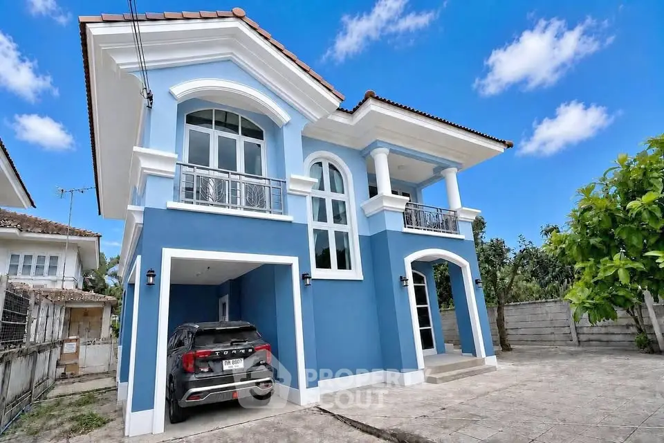 Stunning blue two-story house with elegant arches and spacious driveway