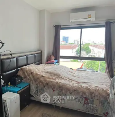 Cozy bedroom with large window offering city view, featuring air conditioning and modern decor.
